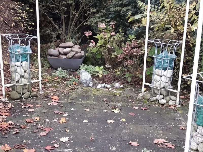 Waschbeton-Terrasse vor der Reinigung, dunkel und fleckig mit Laub